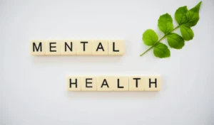 Mental health concept with text arranged on tiles and a green leaf symbolizing wellbeing and emotional balance